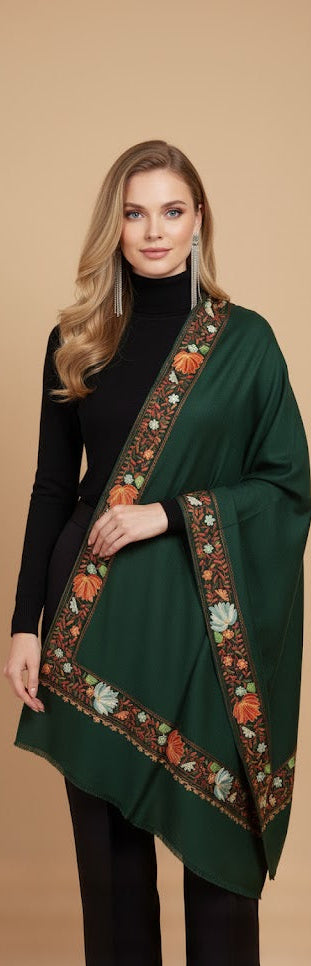 Woman wearing a green embroidered shawl against a beige background