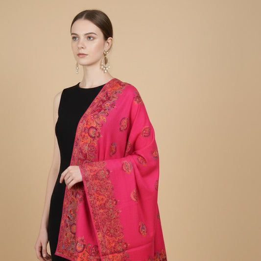 Woman wearing a bright pink scarf with intricate patterns on a beige background