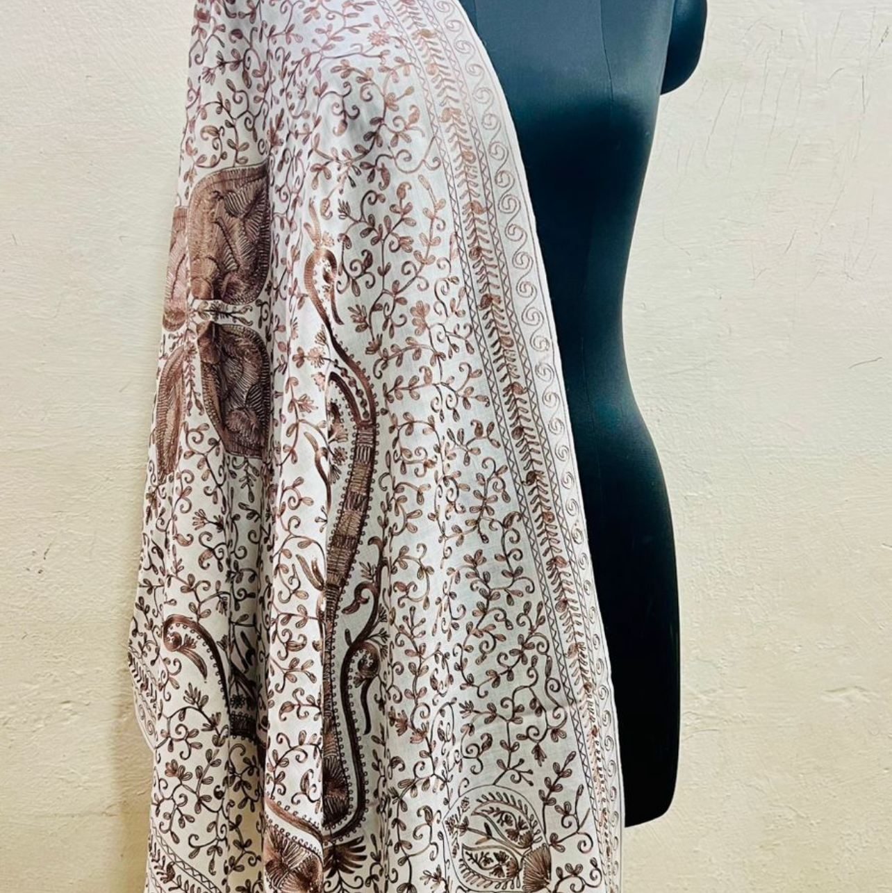 Mannequin wearing a patterned shawl with a plain background