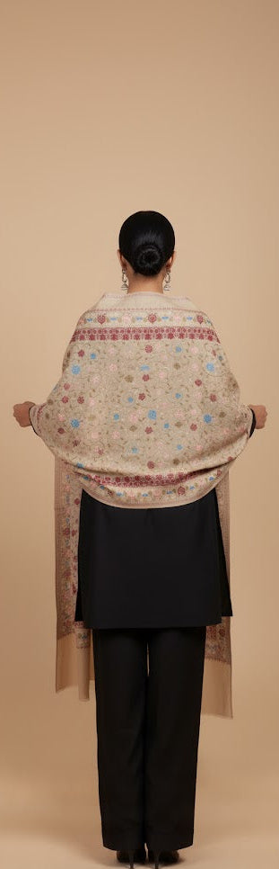 Person wearing a patterned shawl over shoulders on a beige background