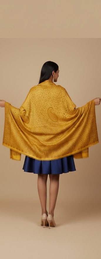 Woman wearing a yellow shawl over a blue dress on a beige background