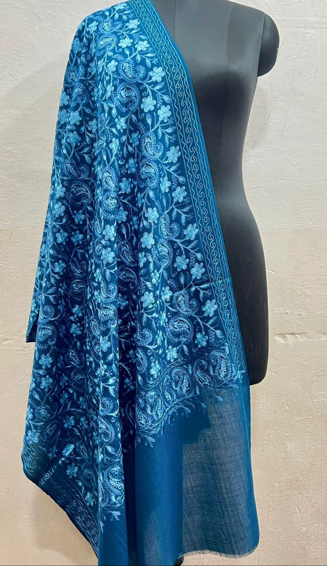 Blue floral patterned scarf draped over a mannequin against a neutral background