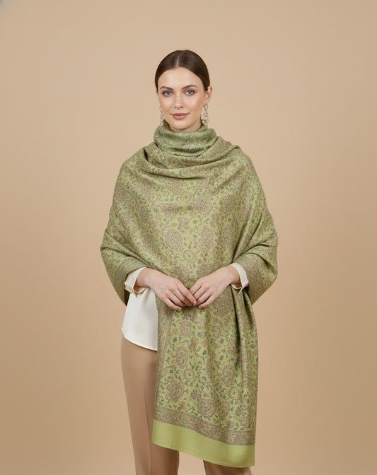 Woman wearing a sage green paisley patterned faux pashmina silk blend on a beige background