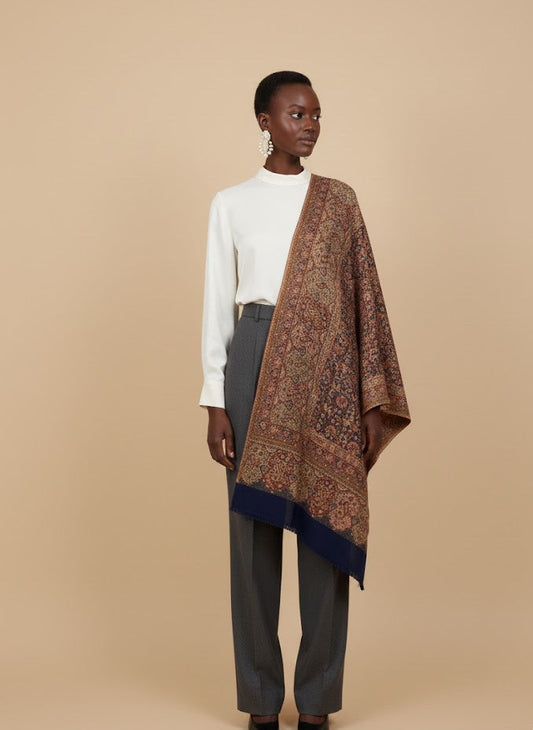 Woman wearing a patterned deep indigo blue hand woven pure wool patterned jamawar kani shawl on a beige background