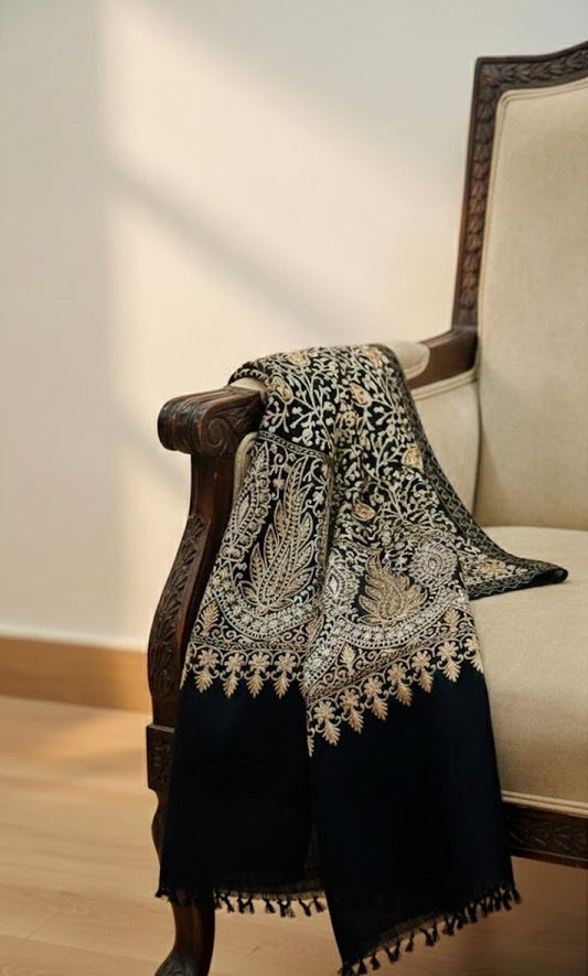 Black and white patterned pashmina shawl draped over a wooden armchair with a beige cushion.