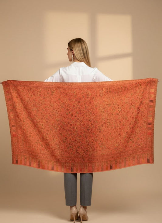 Person holding a large pink patterned shawl against a beige background