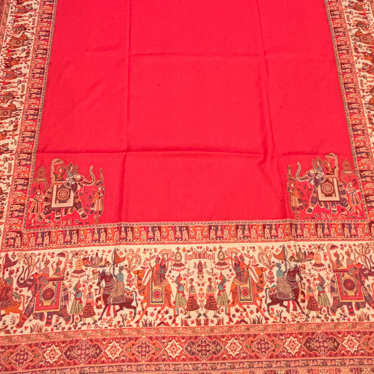 A vibrant pink kalamkari shawl with an ornate traditional patterned border, laid out flat on a light-colored wooden floor.