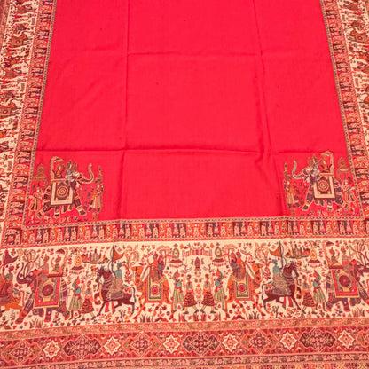 A vibrant pink kalamkari shawl with an ornate traditional patterned border, laid out flat on a light-colored wooden floor.