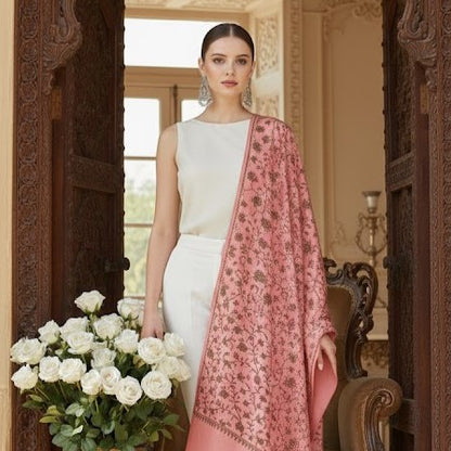 Woman holding a bouquet of white roses, wearing a white outfit with a pink floral shawl, in an elegant interior setting.