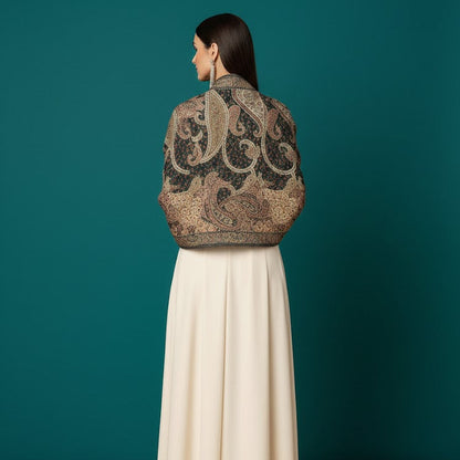 Woman wearing a patterned top and long white skirt against a teal background