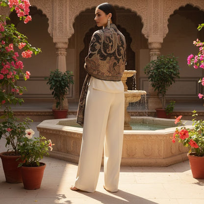 Woman standing in a courtyard with floral decorations and architectural elements.