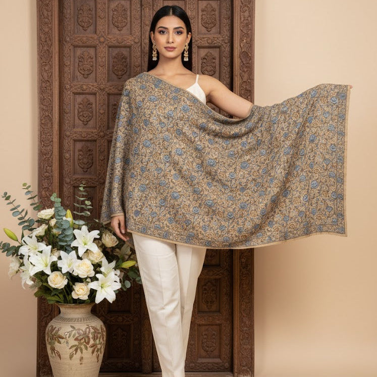 Woman holding a patterned shawl in front of a decorative wooden door with flowers and a vase.