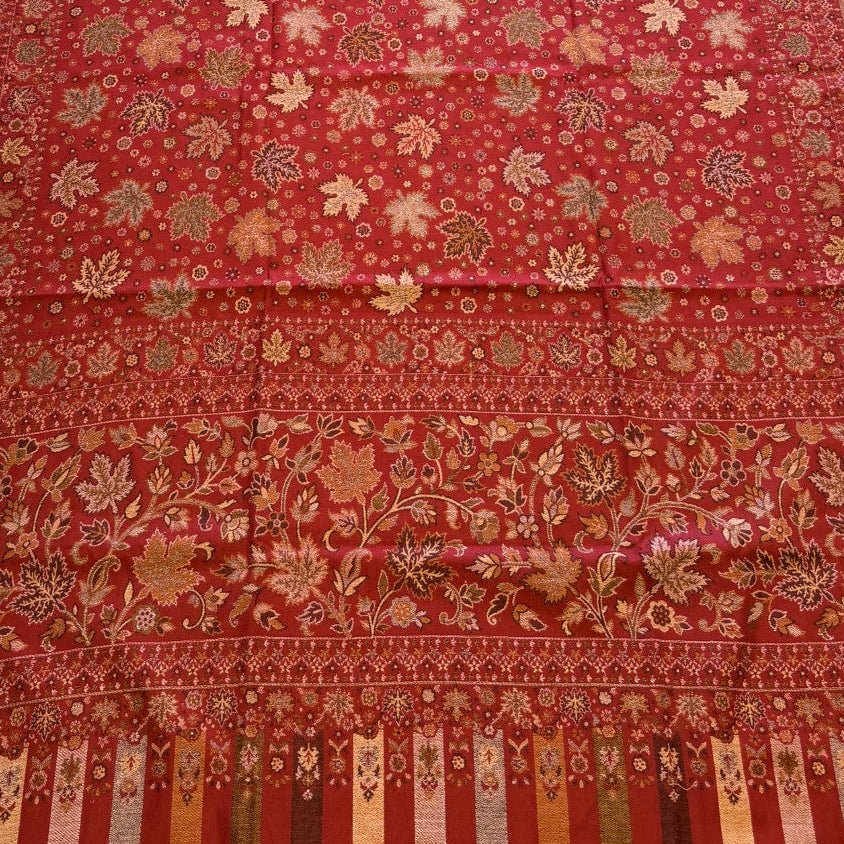 Red patterned shawl on a light-colored floor next to a beige sofa.