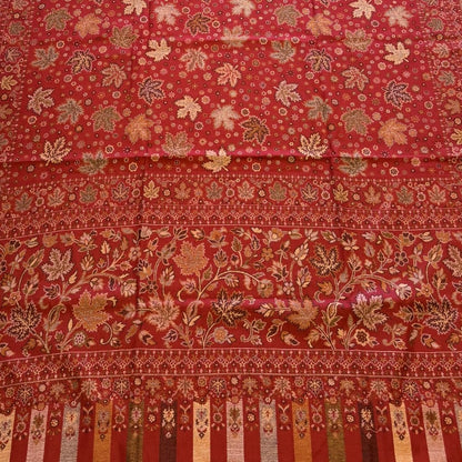 Red patterned shawl on a light-colored floor next to a beige sofa.
