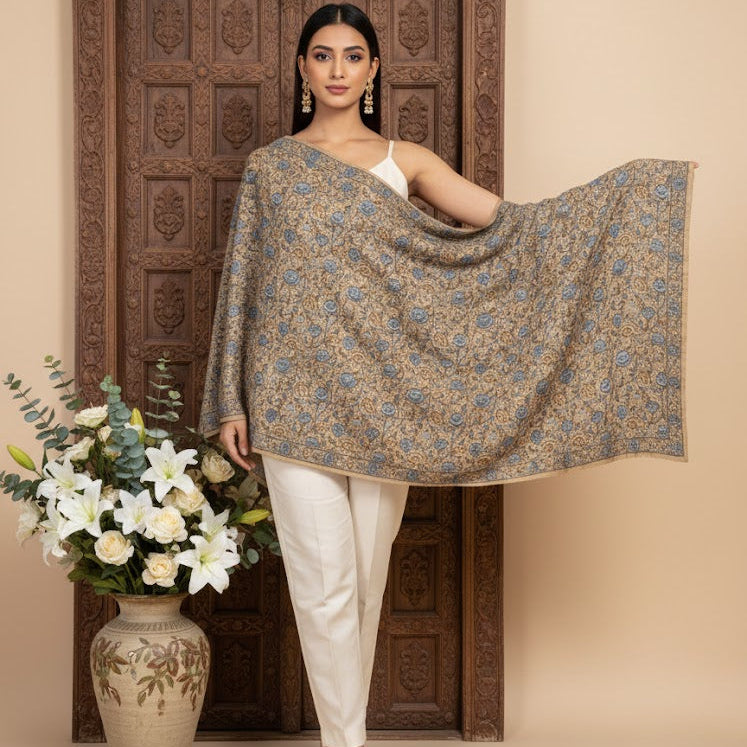 Beautiful Sozni embroidery shawl in beige with blue embroidery draped over a female model standing in a beautiful doorway