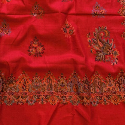 Red fabric with intricate patterns on a carpeted floor