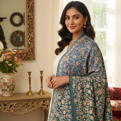 Woman wearing a blue floral traditional outfit in an elegant room.