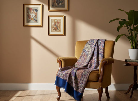 Yellow armchair with a deep indigo blue hand woven pure wool patterned jamawar kani shawl draped over it in a sunlit room.