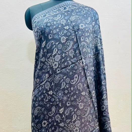 A dark blue-gray sari with a white paisley and floral block print, draped on a black mannequin against a light beige wall.