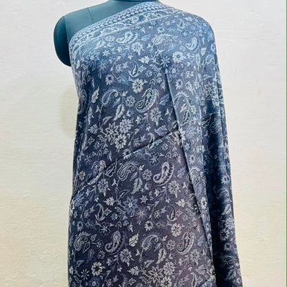 A dark blue-gray sari with a white paisley and floral block print, draped on a black mannequin against a light beige wall.