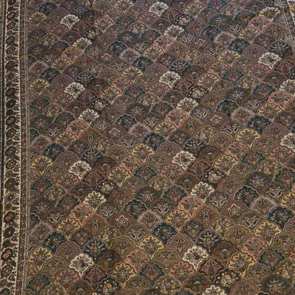 A traditional oriental area rug with an intricate geometric and floral pattern in shades of brown, beige, and muted blue, featuring a decorative border.