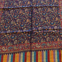 Long, patterned fabric with colorful borders on a wooden floor.