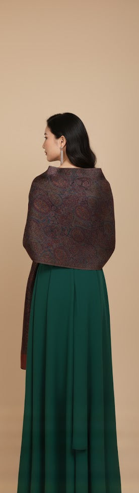 Woman wearing a dark maroon textured stole over a green dress on a beige background