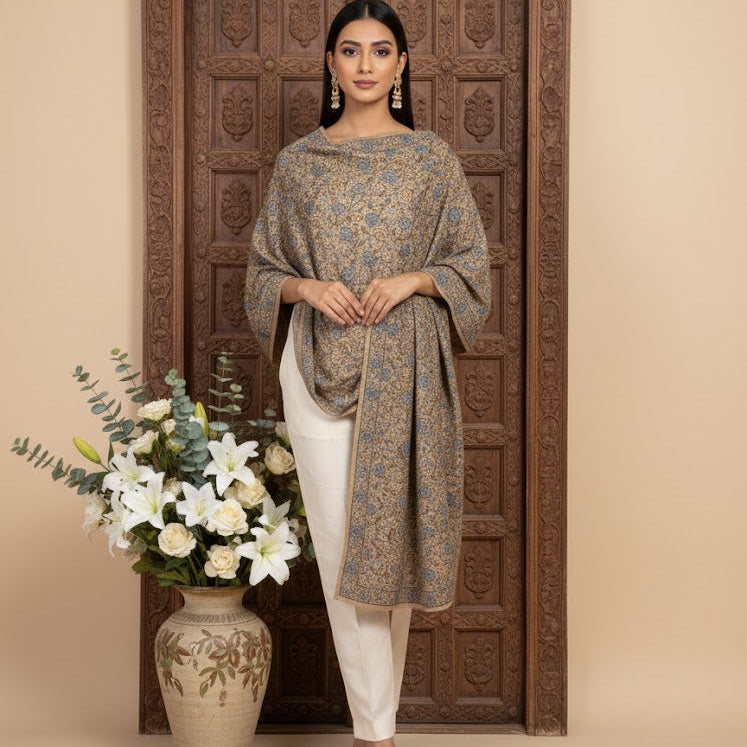 Beautiful Sozni embroidery shawl in beige with blue embroidery draped over a female model standing in a beautiful doorway