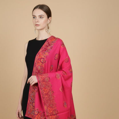 Woman wearing a bright pink scarf with intricate patterns on a beige background