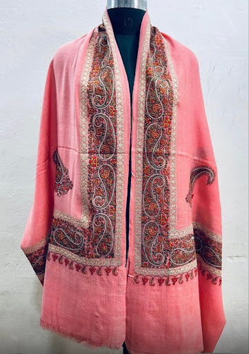 Pink shawl with intricate patterns on a mannequin against a white background