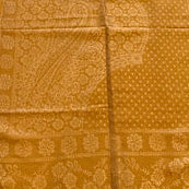 Gold fabric with intricate patterns on a light wooden floor.