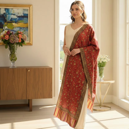 Woman in a red saree standing in a bright room with large windows.