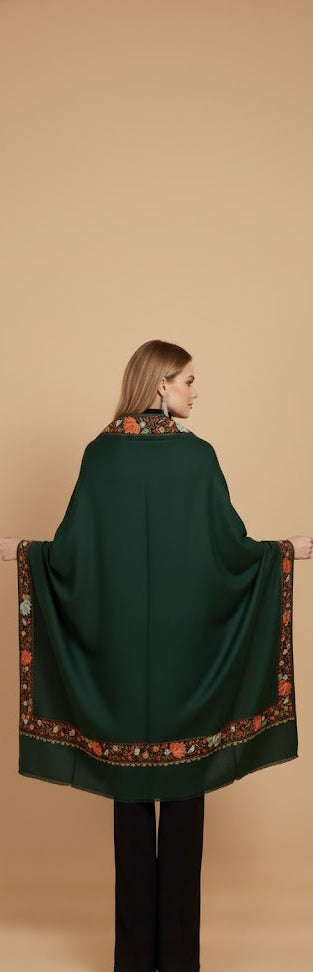 Woman wearing a dark green shawl with a patterned edge on a beige background