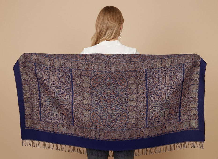 Person wearing a silk wool blend, large patterned jamawar kani shawl against a beige background