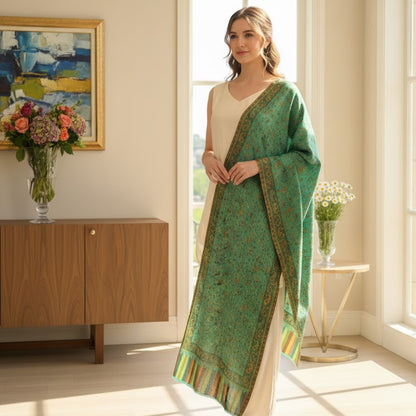 Woman in a green and beige traditional outfit standing in a bright room with large windows.