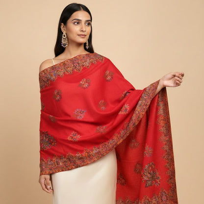 Woman wearing a red saree with intricate patterns on a beige background