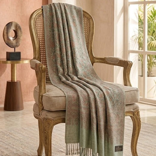 Woven chair with a green and beige plaid blanket draped over it in a room with large windows.