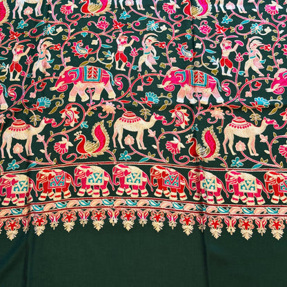 A close-up of a dark green fabric with an intricate hand-block printed pattern featuring pink, red, white, and light blue elephants, floral vines, and a decorative border.