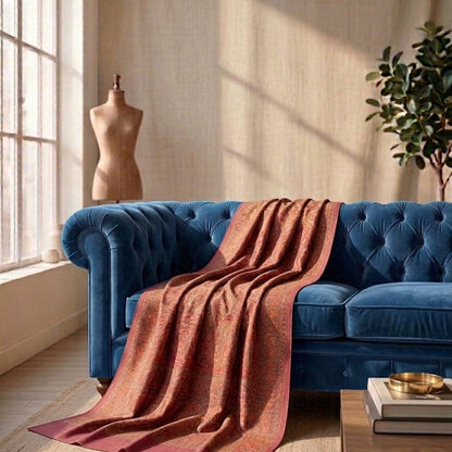 Blue velvet sofa with a rust-colored blanket in a sunlit room.