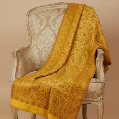 Yellow textured shawl draped over a decorative chair against a beige background
