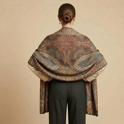 Person wearing a patterned shawl over shoulders against a beige background