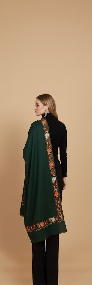 Woman wearing a dark green shawl with floral patterns on a beige background