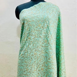 A light green draped fabric with a small beige floral pattern, displayed on a black mannequin torso against a textured beige wall.