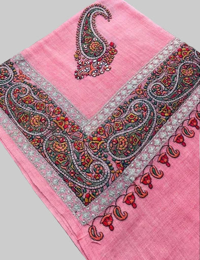 Pink scarf with intricate paisley patterns on a wooden surface