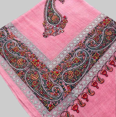 Pink scarf with intricate paisley patterns on a wooden surface