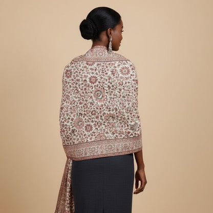 Woman wearing a patterned shawl over a plain garment on a beige background
