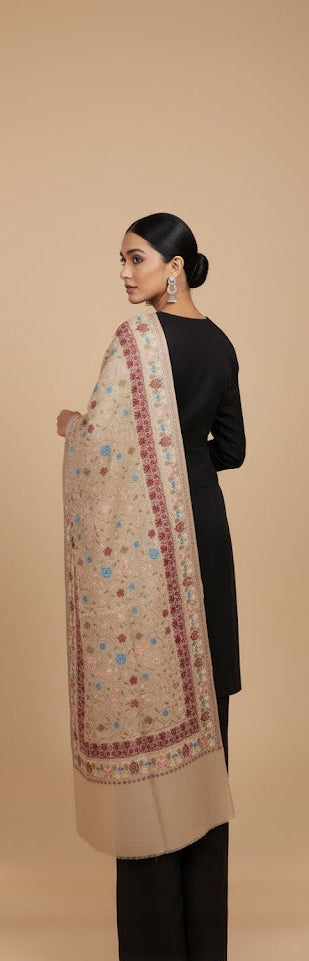 Woman wearing a black kurta with a beige shawl featuring floral patterns on a beige background