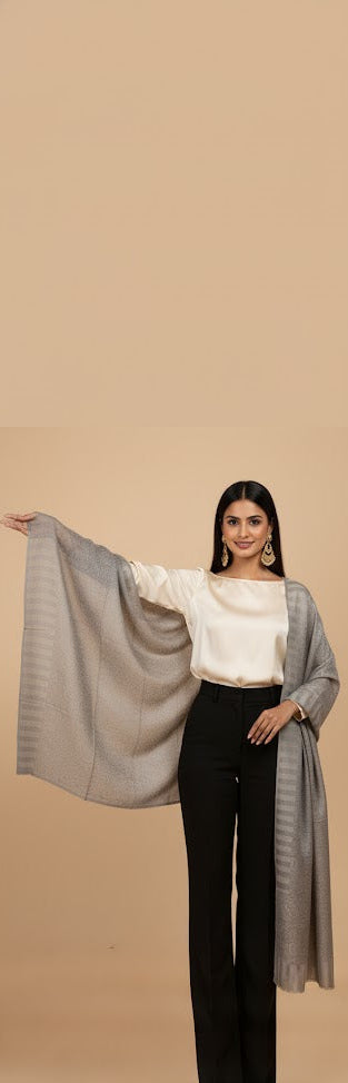 Woman wearing a gray shawl over a white top and black pants on a beige background
