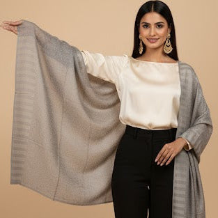 Woman wearing a gray shawl over a white top and black pants on a beige background