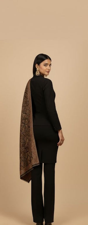 Woman wearing a black outfit with a patterned shawl on a beige background